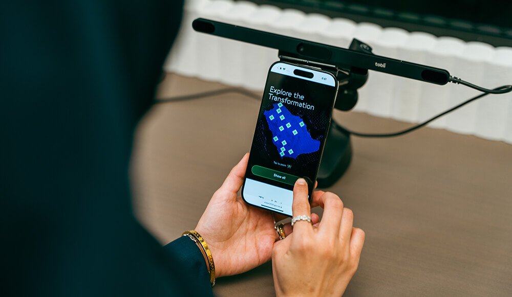 Participant taps a smartphone mounted beneath a Tobii eye-tracking bar during a mobile usability test.