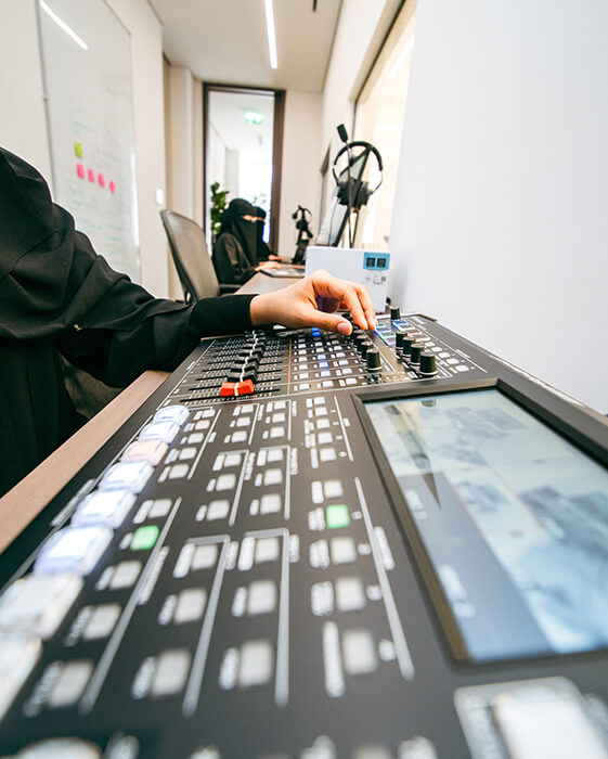 Technician in an observation room adjusts an A/V mixer console to monitor a live usability session.
